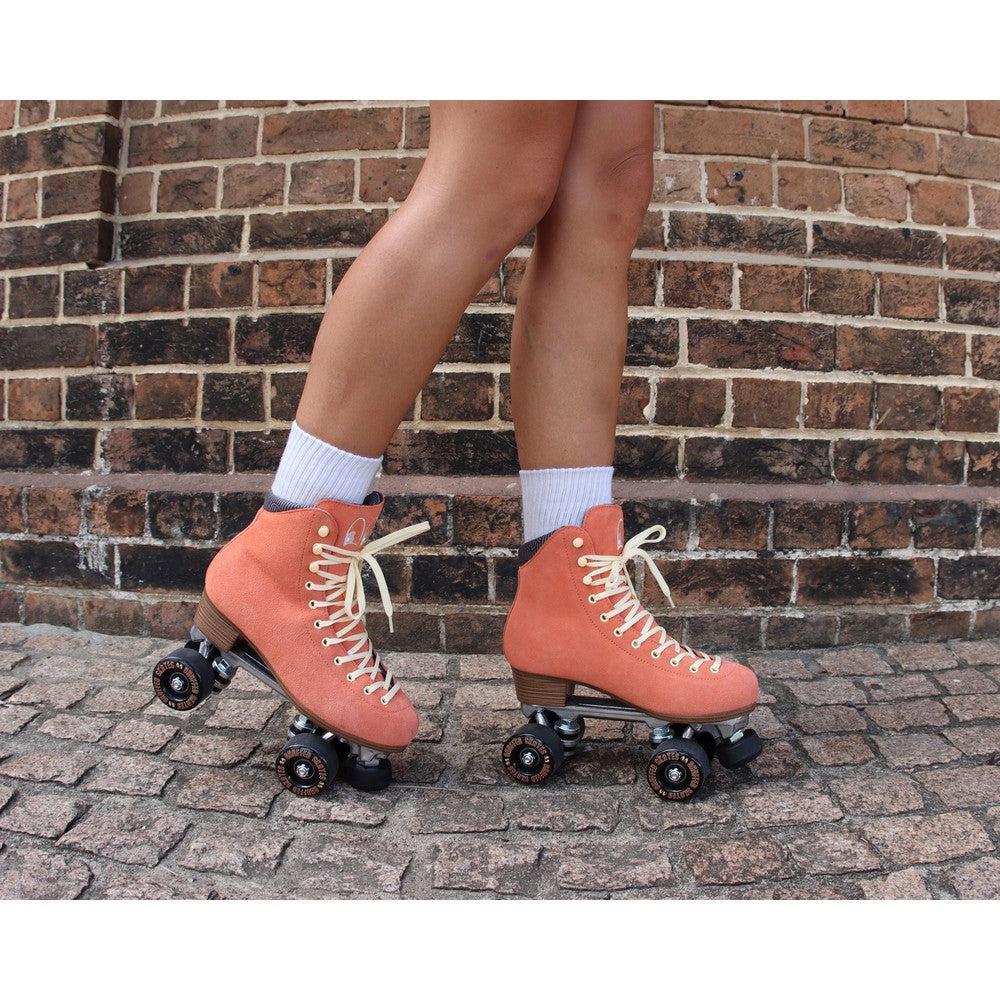 Chuffed Skates peach pink roller skates with brick background